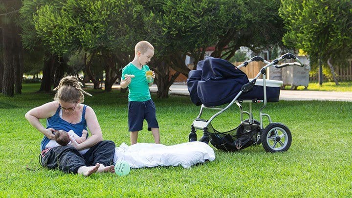 Mom nursing twins in park